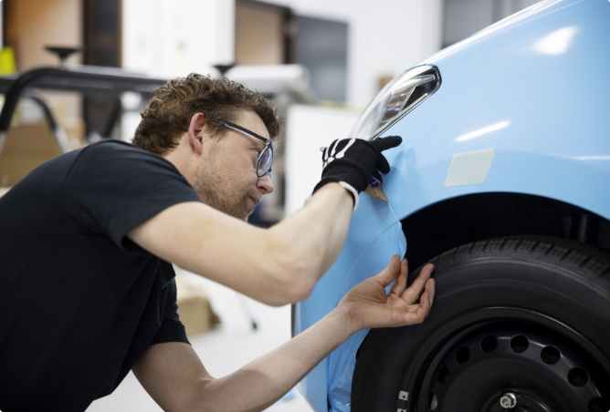 medium-shot-man-wrapping-car-with-blue-cover